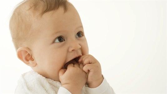 Nærbilde av en baby som putter fingrene i munnen