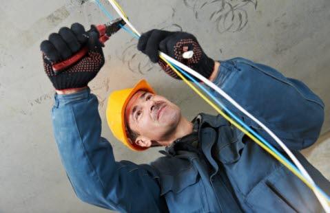 elektrisitet En elektriker med arbeidsutstyr som skal klippe en ledning
