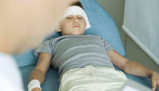 Hodeskade Et pbarn ligger i en sykeseng og har fått bandasje rundt hode