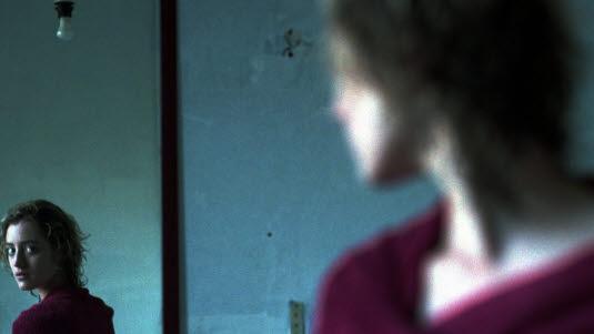 Depresjon Ung kvinne ser på seg selv i et speil