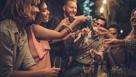 Festing Gruppe pent kledde mennesker skåler og smiler på utendørsfest i hage