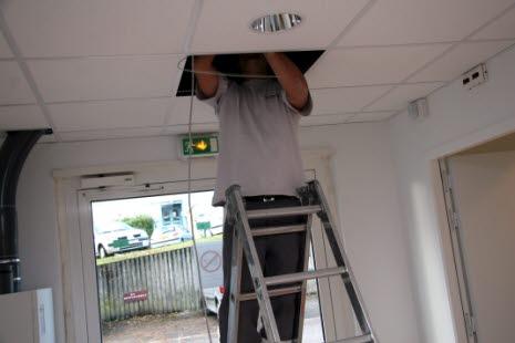 Elektrikeren Elektriker som arbeider med lyset som festet i taket