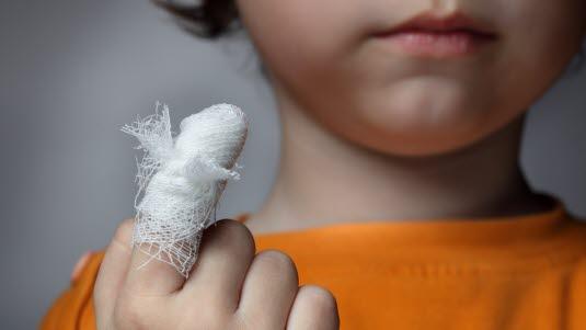 fingerskade,finger,skade.jpg Et barn holder opp sin bandasjerte finger