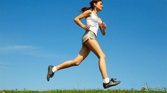 Jogging Dame i treningsklær som jogger på en blomstereng
