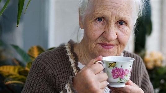 Eldre kvinne Nærbilde av en eldre dame som holder en kaffekopp i porselen
