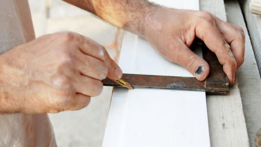 klemt negl.jpg Håndverker med blå negl som lager kappemerke på en planke