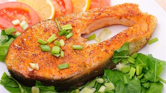 Fisk forebygger hjerneslag Middagstallerken med en laksefilet og oppkuttet grønnsaker som tomat, sitron, spinat og purreløk